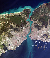 Satellite image showing a thin piece of land, densely populated on the south, bisected by a waterway