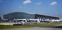 Planes congregate by a building.