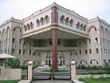 A Four storied, pinkish-grey building with arches and a single pillar in front