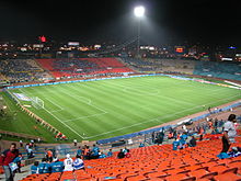 An all-seated roofless stadium with a football pitch.